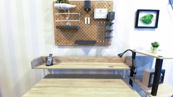 A room with a wooden table, a pegboard wall with various items, a small shelf, and a plant.