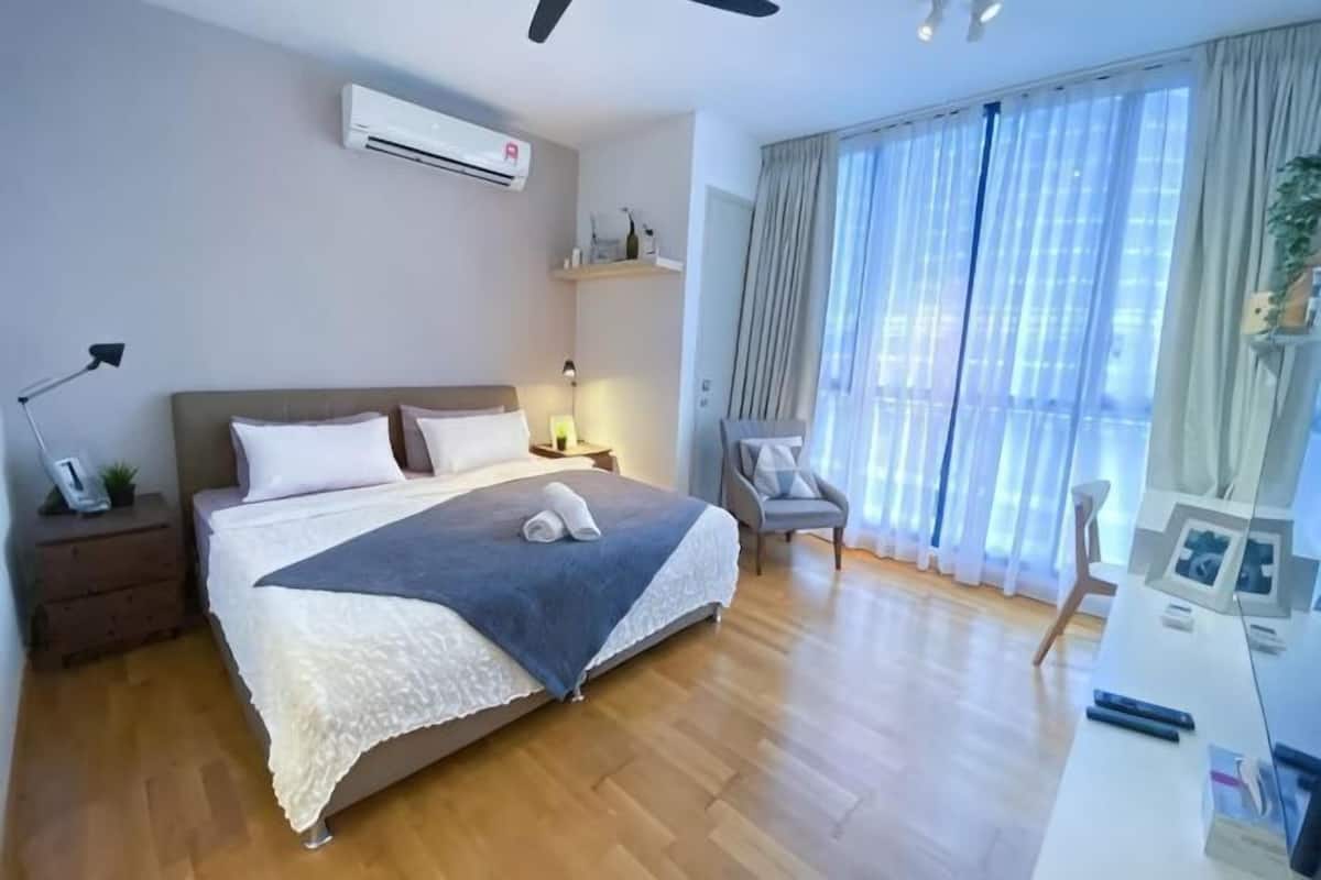 A bedroom with a bed, bedside tables, a desk, a chair, and a window with curtains.