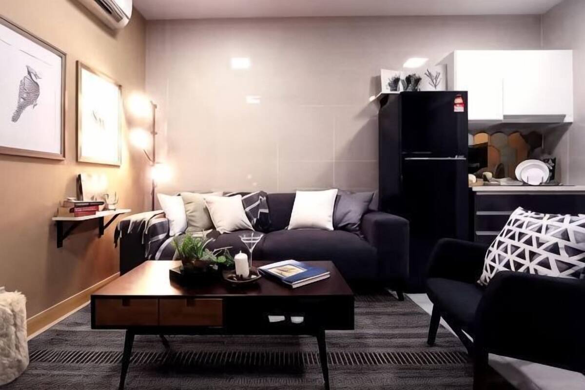 A compact living space with a sofa, a coffee table, a kitchen area, and a refrigerator.