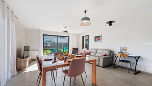 Un salon moderne comprenant une table à manger, des chaises, un canapé et un téléviseur.
