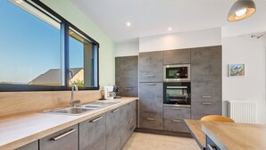 Une cuisine moderne dotée d’une grande fenêtre, d’appareils électroménagers intégrés et d’un plan de travail en bois.