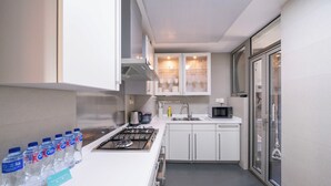 Una cocina moderna con armarios blancos, una estufa de acero inoxidable y un microondas.