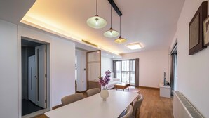 Un comedor moderno con una mesa blanca, sillas y lámparas colgantes.