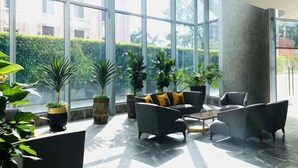 A spacious indoor area with large windows, modern furniture, and potted plants. - Homie Panorama Beachfront Residences Nha Trang (Nha Trang)