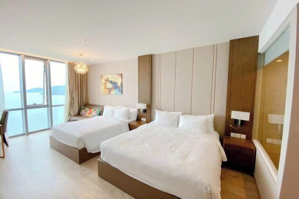 Ein Hotelzimmer mit zwei Betten, einem großen Fenster und Meerblick.