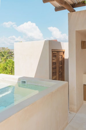 A spa area with a hot tub, a wooden door, and a view of greenery. - Punta Morelos (Brisas de Zicatela)
