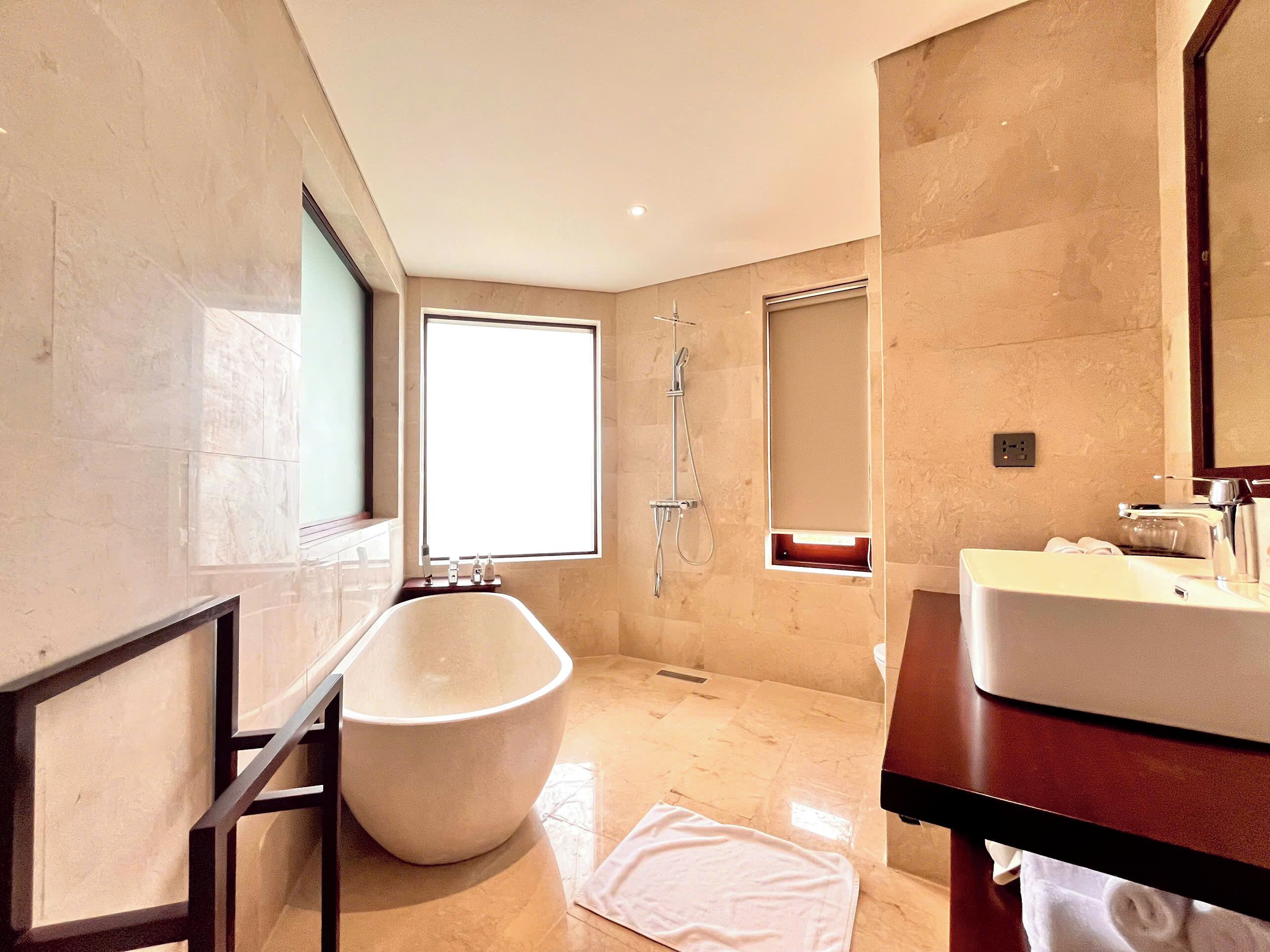 Un baño moderno con una bañera independiente, un espejo grande y una ventana que proporciona luz natural.