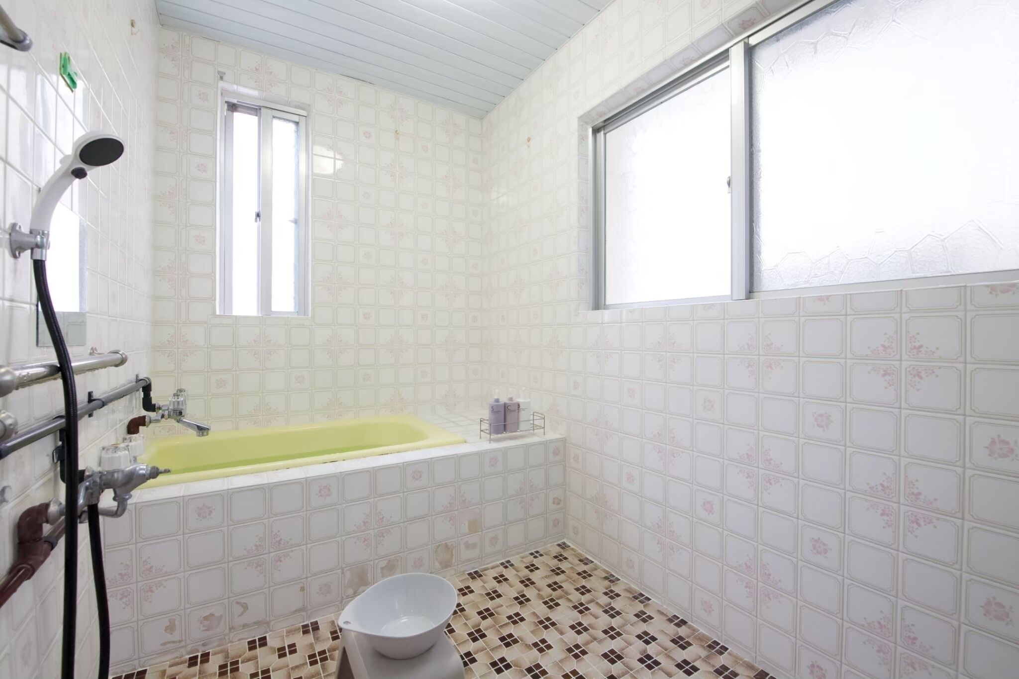A bathroom with a bathtub, a window, and a shower.
