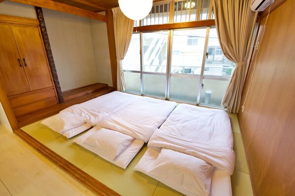 Een kamer met een groot bed, een houten garderobe en een raam met gordijnen.