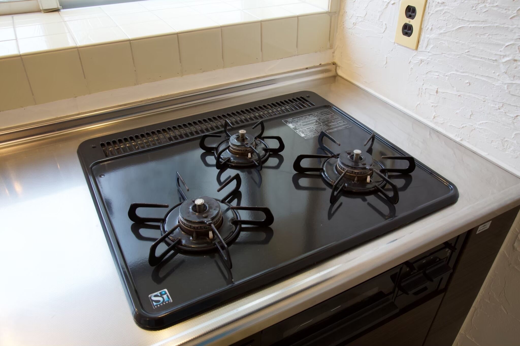 Een keuken met een zwart fornuis en witte aanrechtbladen.