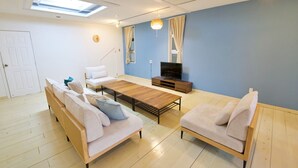A modern living room with a sofa, a coffee table, and a TV. - ITOMAN IN (Itoman)