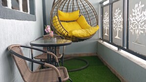 A balcony with artificial grass, a hanging chair with yellow cushions, wicker chairs, and a small table. - Eve's Vista 2 bedroom apartment, Nanyuki- Kenya (Nanyuki)