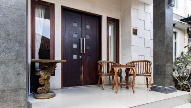 A building entrance with a dark wooden door, a small table with two chairs, and a decorative column.