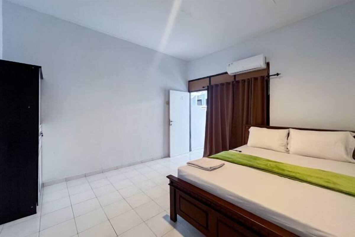 A bedroom with a bed, a wardrobe, a door, and an air conditioning unit.