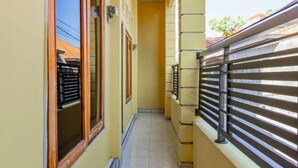 A narrow corridor with a tiled floor, a wooden door, and a metal railing.