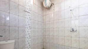 A bathroom with a toilet, a shower with a wall-mounted faucet, and a patterned tile backsplash.