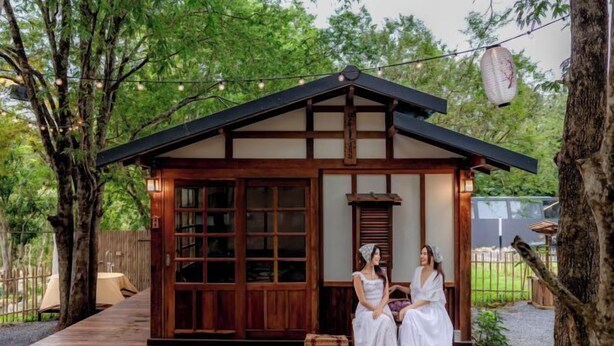 A traditional wooden building with a sloped roof, large glass windows, and a small porch area. - Tanuki house Khaoyai (Pak Chong)
