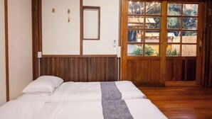 A room with a bed, wooden walls, a window, and a view of greenery outside. - Tanuki house Khaoyai (Pak Chong)