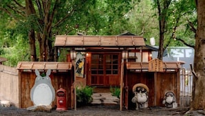 A rustic wooden structure with a traditional Japanese aesthetic, featuring a central entrance and decorative elements like animal figures. - Tanuki house Khaoyai (Pak Chong)