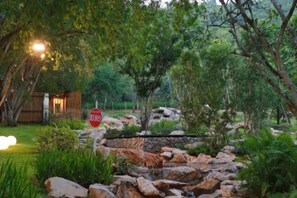 A natural outdoor area with a stone pathway, trees, and a wooden structure.