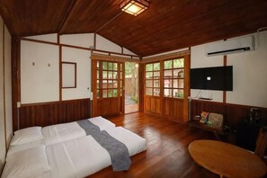 Een traditionele Japanse kamer met tatami vloerbedekking, een futon bed, schuifdeuren en een televisietoestel.