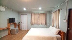 A room with a bed, a television on a stand, a door, and curtains. - ID Garden Home (Lampang)