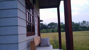 A porch with a bench and a view of a field. - ID Garden Home (Lampang)
