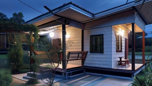 A modern house with a covered porch, a seating area, and a well-maintained garden. - ID Garden Home (Lampang)