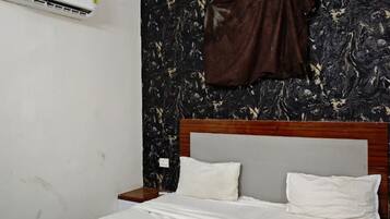 A bedroom with a bed, a ceiling fan, an air conditioning unit, and a marble-patterned wall.