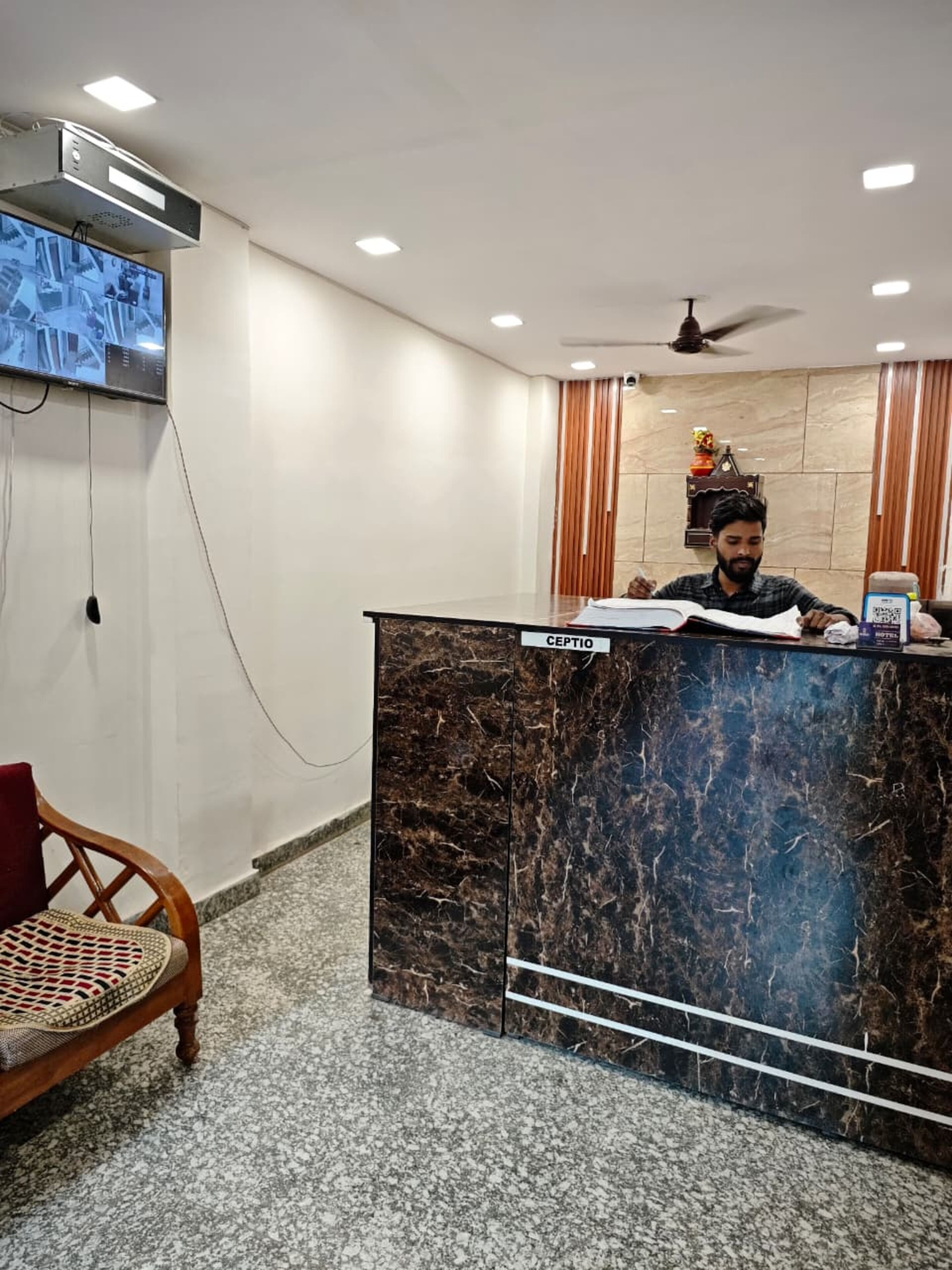 A reception desk with a marble top, a ceiling fan, and a television mounted on the wall.