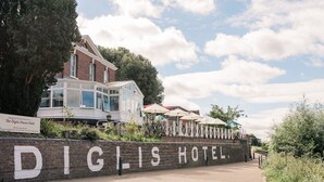 A brick wall with "DIGLIS HOTEL" written on it, leading to a building with a glass conservatory and outdoor seating area. - Diglis House Hotel (Worcester)