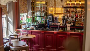A bar area with wooden chairs, a bar counter, and shelves stocked with bottles and glasses. - Diglis House Hotel (Worcester)