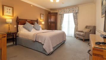 A bedroom with a large bed, a nightstand, a dresser, a chair, and a window with curtains.