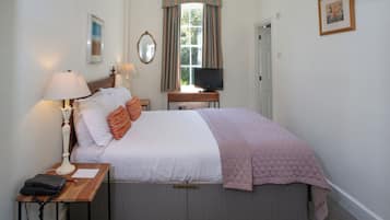 A bedroom with a bed, bedside lamps, a desk with a telephone, a television, and a window with curtains.