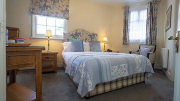 A bedroom with a bed, bedside tables, a desk, and a window with curtains.