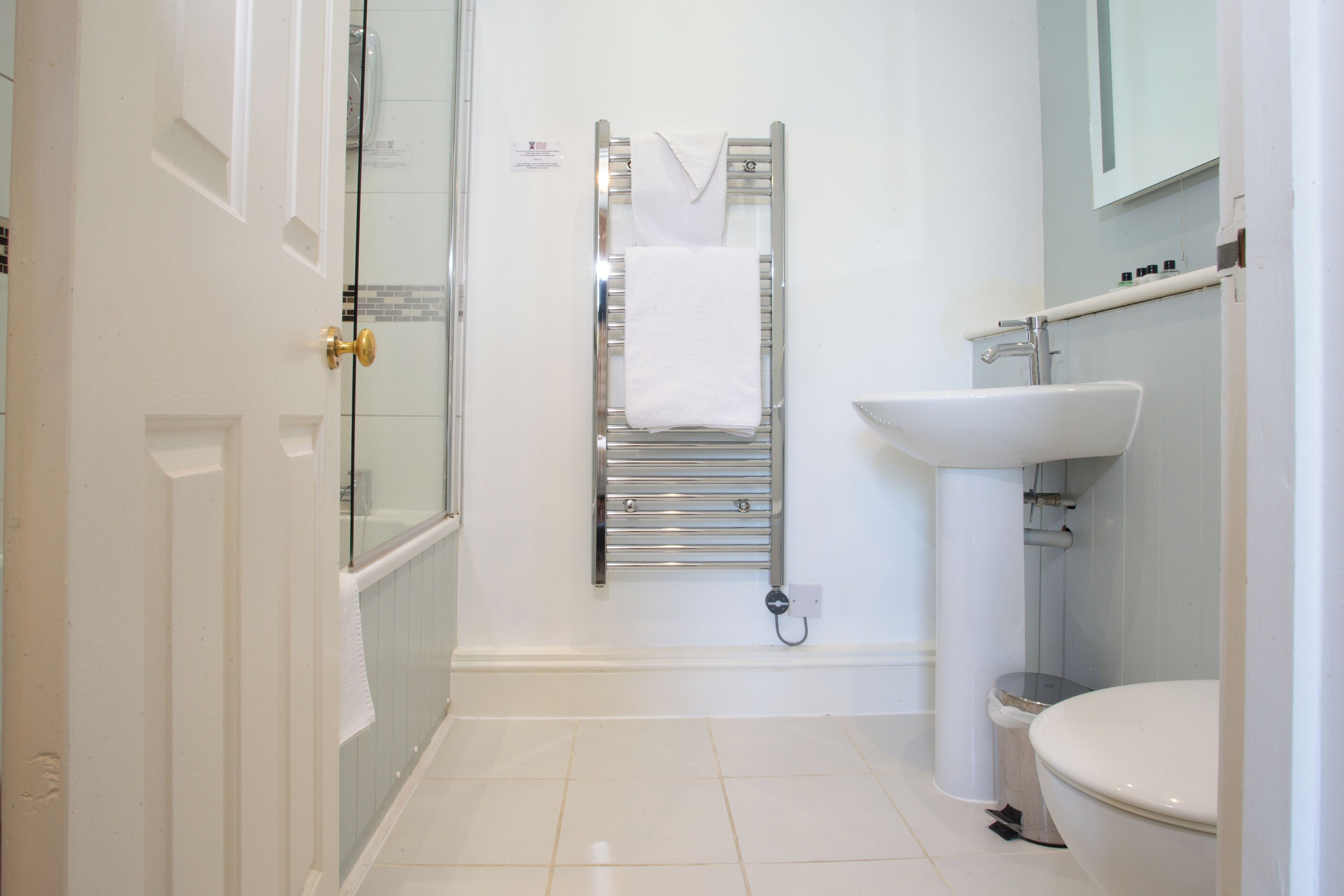A bathroom with a glass shower enclosure, a white sink, and a towel rack.
