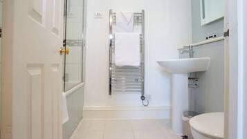 Un baño con cabina de ducha de vidrio, un lavabo blanco y un perchero para toallas.