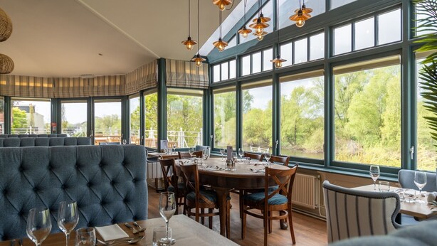 A restaurant with large windows, a high ceiling, and a view of greenery outside. - Diglis House Hotel (Worcester)