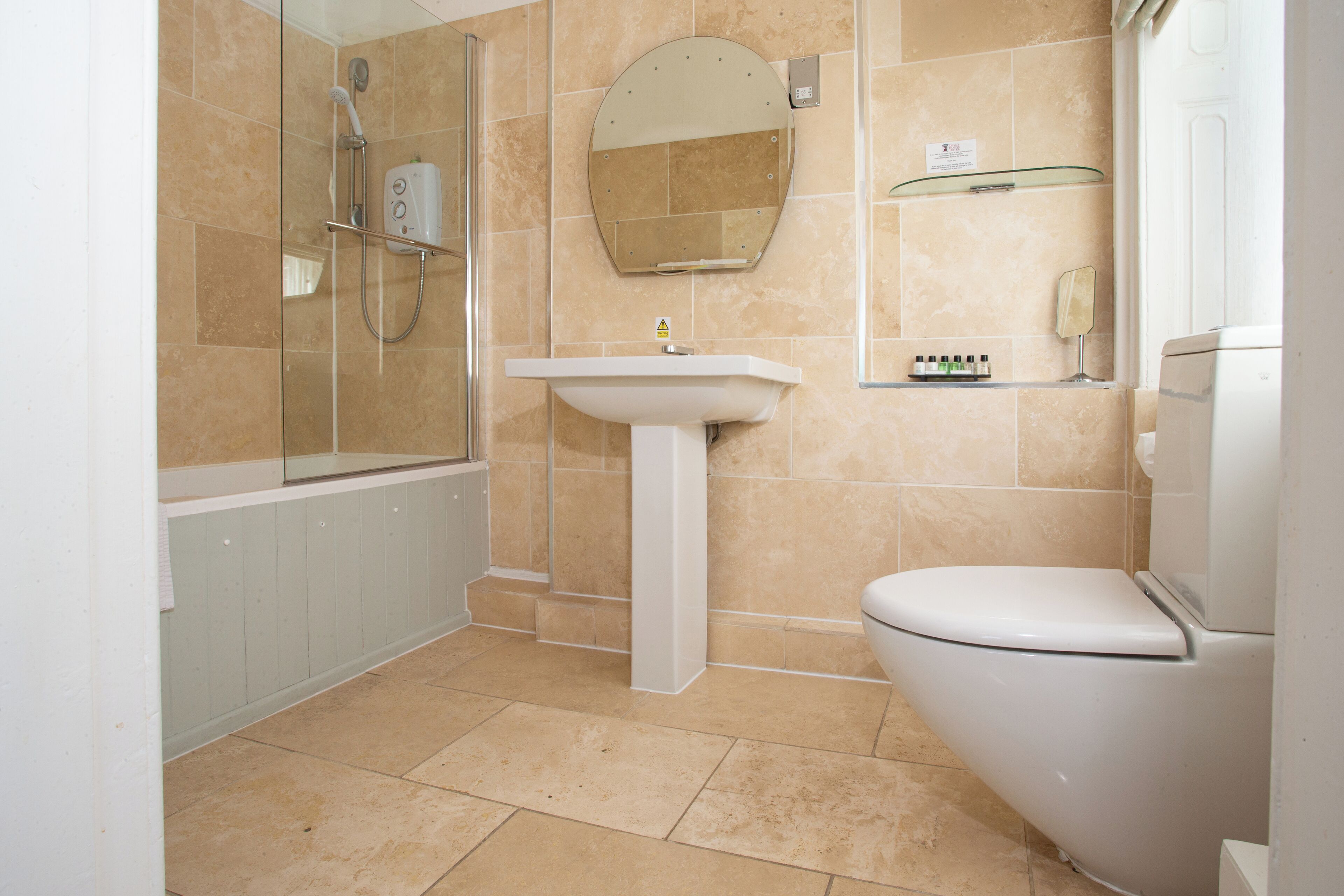 A bathroom with a shower, sink, toilet, and a mirror.