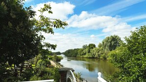 A riverside walkway with a bridge, surrounded by lush greenery and trees. - Diglis House Hotel (Worcester)
