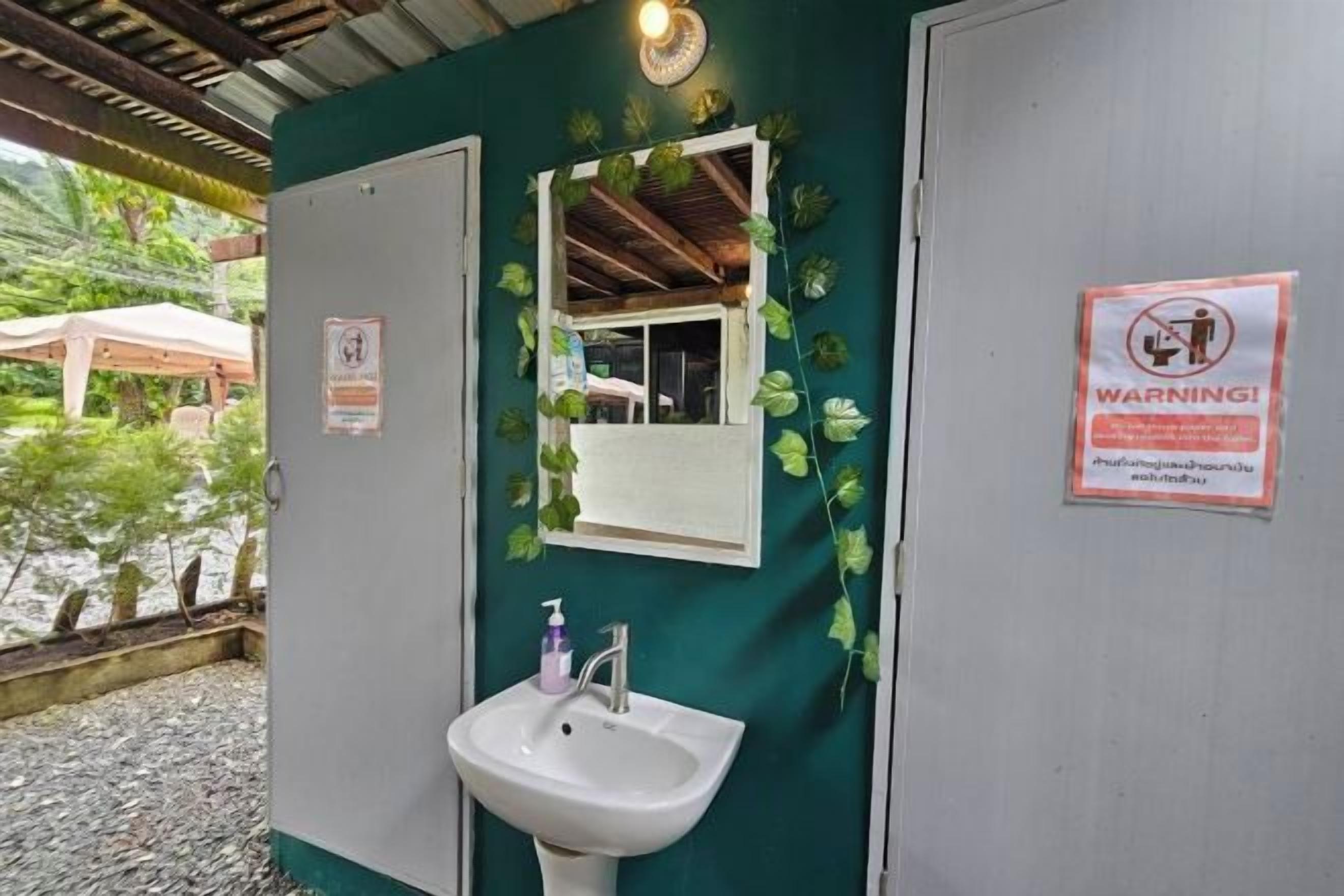 A bathroom with a white sink, a mirror, and a warning sign.