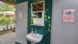 Une salle de bain avec un lavabo blanc, un miroir et un panneau d’avertissement.