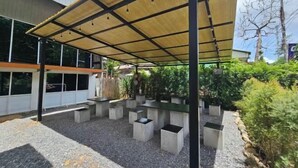 Un área de estar al aire libre con macetas de concreto y una estructura de toldo.