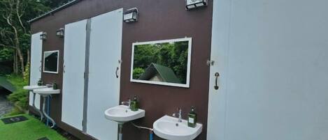 Una hilera de baños privados con lavamanos y espejos individuales.