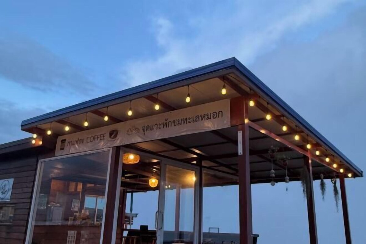 A coffee shop with a covered outdoor seating area and a sign in a foreign language.