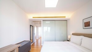 A modern hotel room with a large bed, a bedside table, a desk, and a wardrobe. - Tyms Family 3BR 2BA Apt Xujiahui Metro (Shanghai)