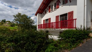 Un bâtiment blanc avec des volets rouges et un balcon.