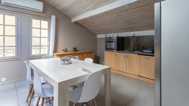 Une cuisine moderne avec des meubles en bois, une table à manger avec des chaises et un four encastré.