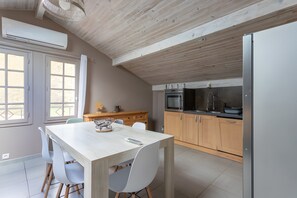 Une cuisine moderne avec des meubles en bois, une table à manger avec des chaises et un four encastré.
