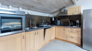 Une cuisine moderne avec des meubles en bois, des appareils électroménagers en acier inoxydable et un lave-vaisselle apparent.
